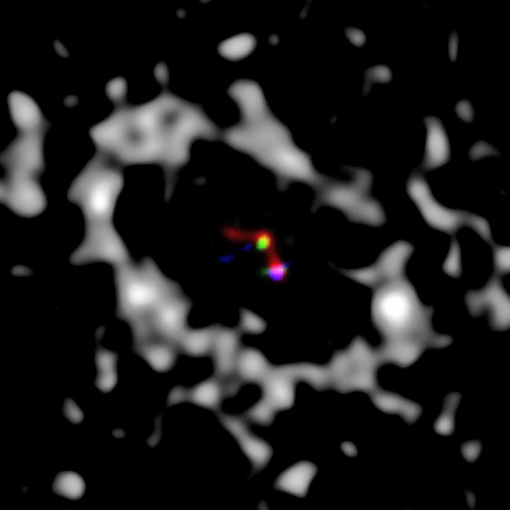 Image shows a composite where blue represents the MagAO data taken at H-alpha, and green and red show the LBT data taken at Ks and L&#039; bands. The greyscale is a previously published millimeter image of the disk.