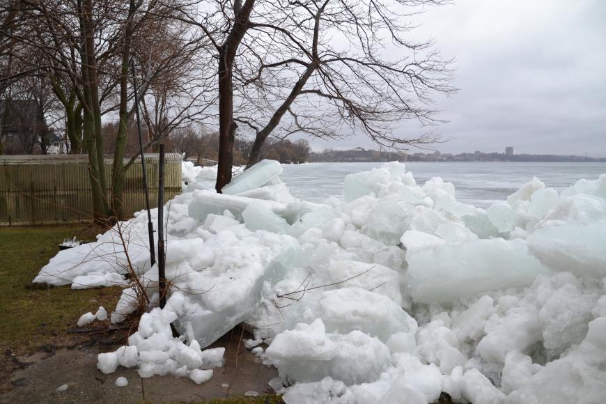 Giant, thick sheets of ice piled up on the shoreline of a lake.