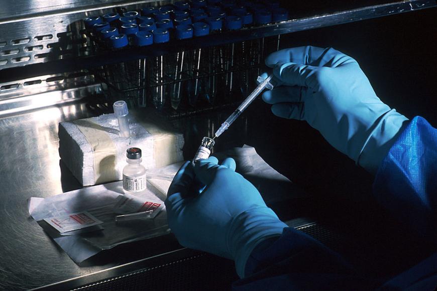 gloved hands prepare a dose of vaccine in a syringe