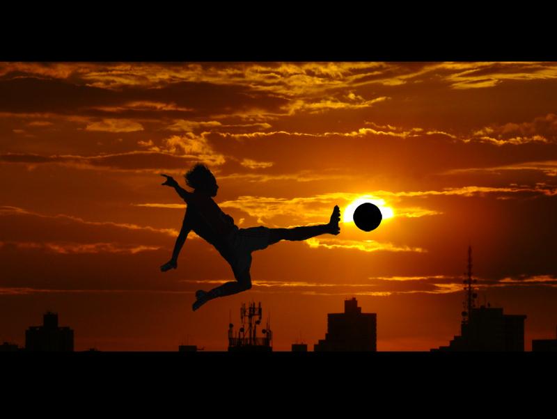 Football (soccer) silhouette against sunset.