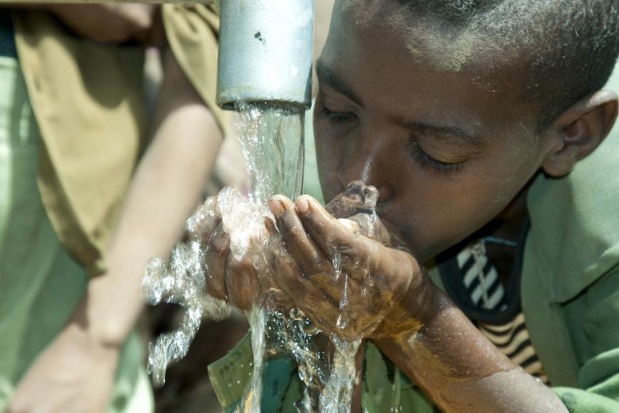 Boy drinking water from a pump