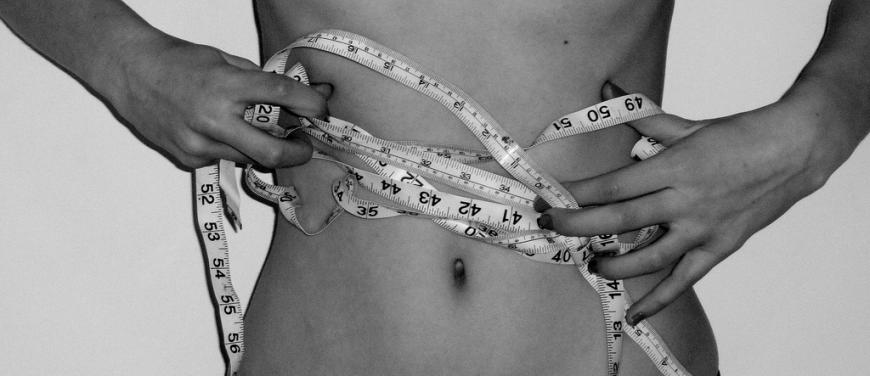 black and white photo of a woman&#039;s bare stomach wrapped in a measuring tape
