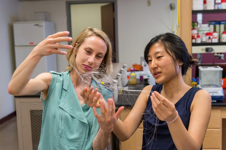 Two researchers hold up a fine mesh