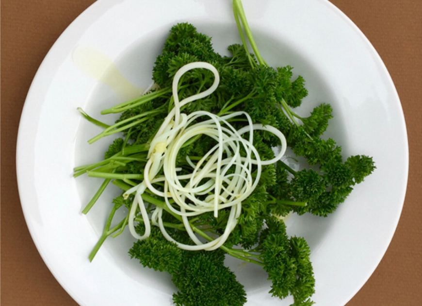a plate of fresh parsley with cooked spaghetti on top