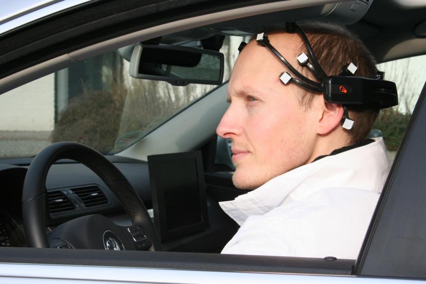 photograph of a man in the driver&#039;s seat of a car wearing an elaborate headset.