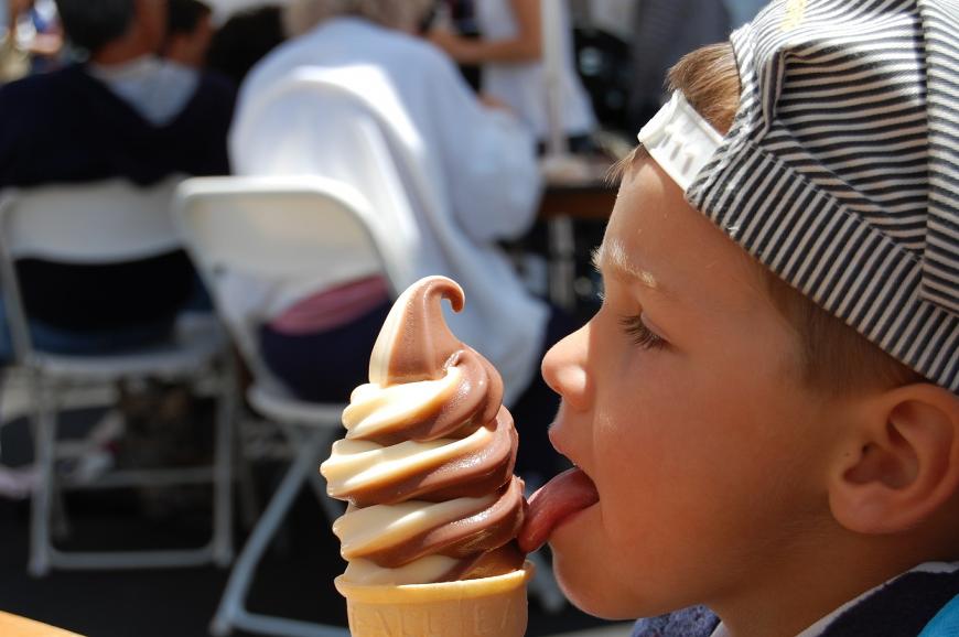 Young boy licking an ice cream cone.