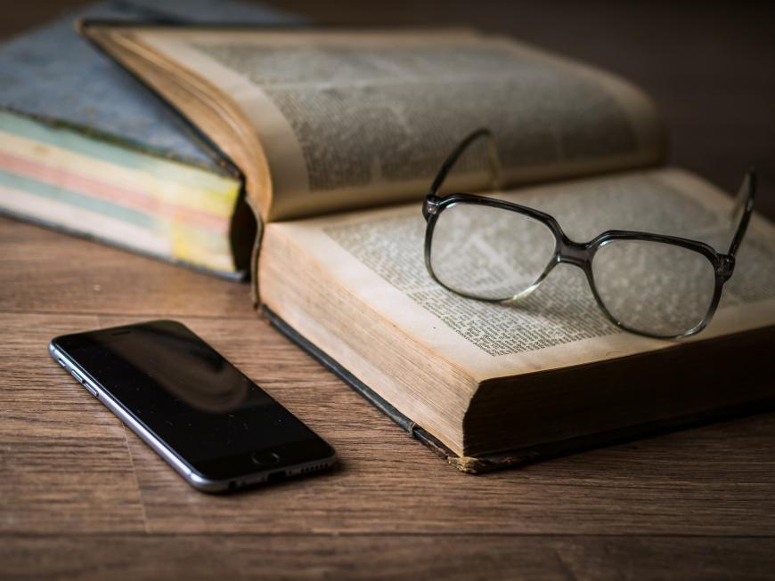 Smartphone, glasses, and books on a desk