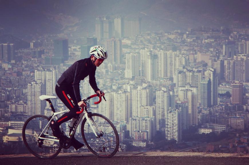 Cyclist riding on a hill above a smoggy metropolitan city