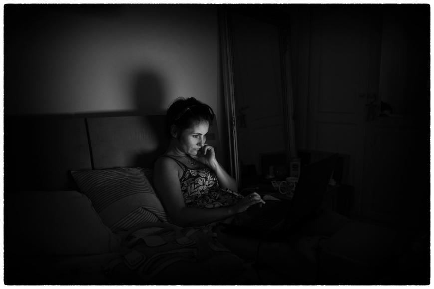 Woman in bed, in the glow of her phone.