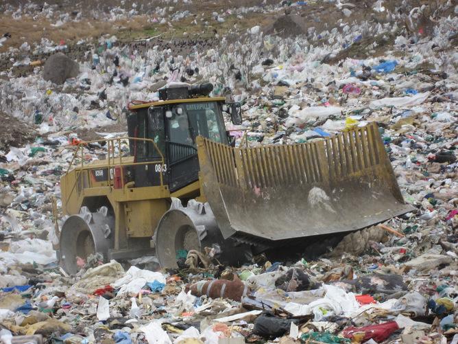 a bulldozer moving trash at a garbage dump