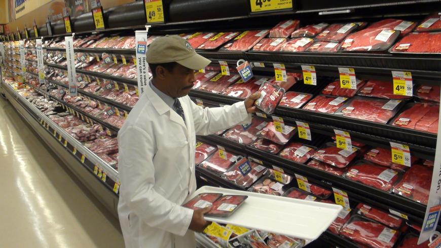 Grocery store employee restocking shelves in the meat aisle