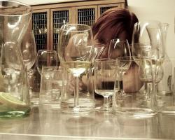 Woman staring through a group of empty glasses on a table.