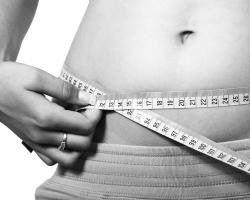Woman measuring waist. Black and white photo.