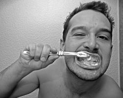 Man brushing teeth in front of bathroom mirror