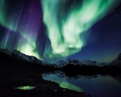 Northern lights over mountains and calm lake. CREDIT: EHRENBERG Kommunikation / Flickr (CC BY 2.0)