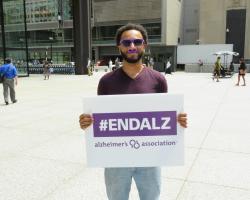 Man holds sign supporting Alzheimer&#039;s research