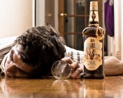Man passed out drunk on the floor with a bottle of Amarula