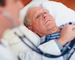 Doctor checks heart rate of elderly patient with stethoscope