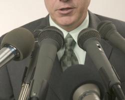 Man speaking into journalists&#039; microphones