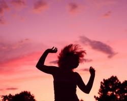 Silhouette of a dancing woman against a sunset