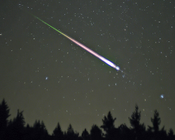 A meteor falls above the treeline
