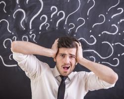 A man panicking with question marks around his head