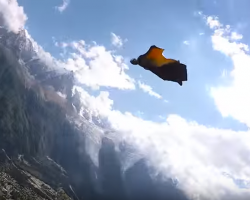 Screenshot of a wingsuit flier in the air above a small town surrounded by moutains