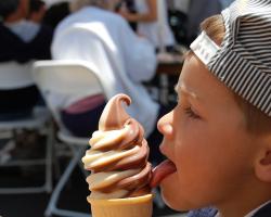 Young boy licking an ice cream cone.