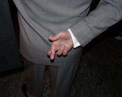 Man in a suit with his fingers crossed behind his back