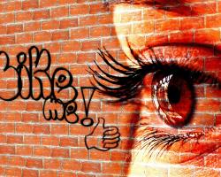 Graffiti on a brick wall. &quot;Like Me!&quot; Close up of an eye
