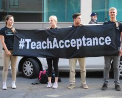 Protests hold a banner reading &quot;#TeachAcceptance&quot;