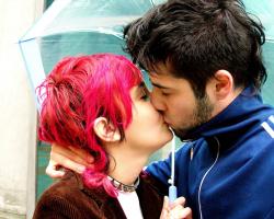 A young couple kissing under an umbrella