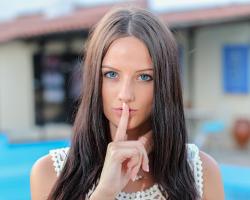 Woman indicating silence with finger over her mouth. Hush