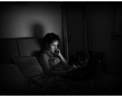 Woman in bed, in the glow of her phone.